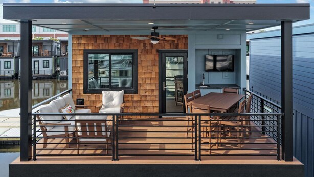 Une terrasse extérieure moderne avec un mur en bois, une table à manger et un canapé.