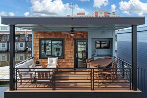 Um terraço moderno ao ar livre com parede de madeira, uma mesa de jantar e um sofá.