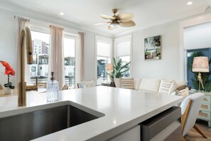 Una cocina moderna con una isla central, un ventilador de techo y vistas de la ciudad a través de grandes ventanales.