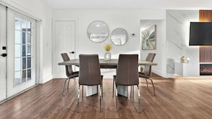 A dining area with a table, chairs, and a TV mounted on the wall. - Fun Miami Pool Home  Pickable, Firepit, Pingpong (Miami)