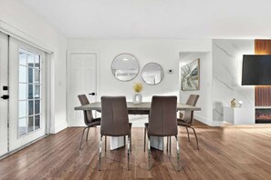 A dining area with a table, chairs, and a TV mounted on the wall. - Fun Miami Pool Home  Pickable, Firepit, Pingpong (Miami)