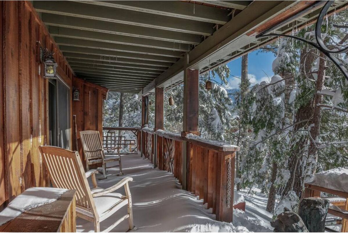 A wooden porch with a view of snow-covered trees.