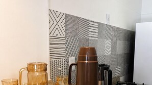A kitchen counter with a coffee maker, glass cups, and a tray of teapots. - Fully Furnished Duplex Apartment in Porto Seguro - Swimming Pool - 200m from the Beach (Porto Seguro)