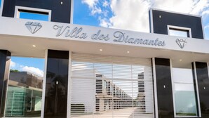 A modern building with a sign reading 'Villa dos Diamantes.' - Fully Furnished Duplex Apartment in Porto Seguro - Swimming Pool - 200m from the Beach (Porto Seguro)