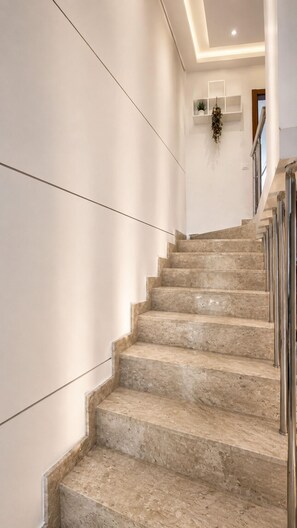 A marble staircase with a handrail, white walls, and a ceiling light. - Fully Furnished Duplex Apartment in Porto Seguro - Swimming Pool - 200m from the Beach (Porto Seguro)