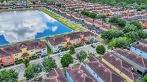 Um bairro residencial com várias casas, um lago central e céu claro.