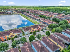 Ein Wohngebiet mit mehreren Häusern, einem zentralen Wasserspiegel und blauem Himmel.