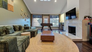A modern living room with a sofa, a wooden coffee table, a fireplace, and a television mounted on the wall. - Kirby Poolhouse - Game Room - Garage - Elevator (Houston)