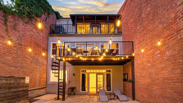 A two-story building with a balcony, a pool, and string lights. - Kirby Poolhouse - Game Room - Garage - Elevator (Houston)