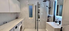 A modern bathroom with a glass shower enclosure, a built-in sink, and a window. - Villa Apartment in the best part of Gothenburg (Gothenburg)
