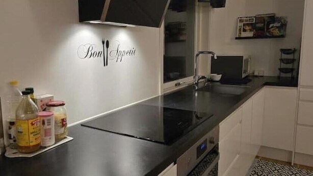 A kitchen with a black countertop, a stainless steel appliance, and a wall-mounted sign that reads 'Bon Appetit.' - Villa Apartment in the best part of Gothenburg (Gothenburg)