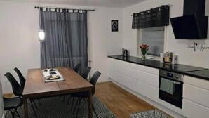 A compact kitchen with a dining table, chairs, a built-in oven, and a small refrigerator. - Villa Apartment in the best part of Gothenburg (Gothenburg)