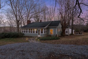 A house with a porch, a chimney, and a small shed.