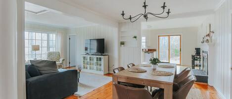 Een ruime woonkamer met een eettafel, stoelen, een bank en een televisie.