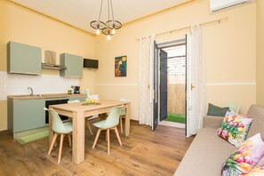A compact living space with a kitchenette, dining area, and a sofa with floral cushions.