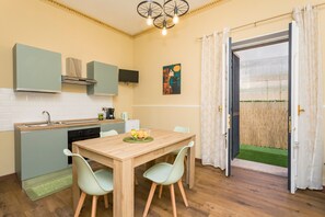 A compact kitchen with a dining area, a television, and a painting on the wall.