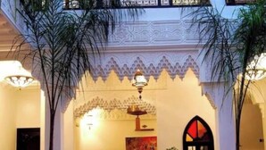 A traditional interior with a decorative archway, a chandelier, and a door with stained glass.