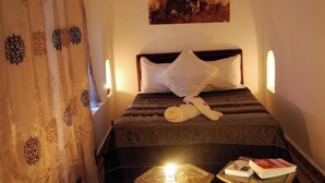 A bed with a rolled towel, a bedside table with a book, and a painting above the bed.