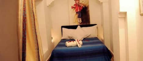 A bedroom with a bed, a small table with a candle, a book, and a decorative item.