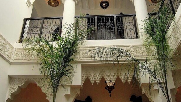 A multi-level interior with ornate arches, balconies, and hanging plants.