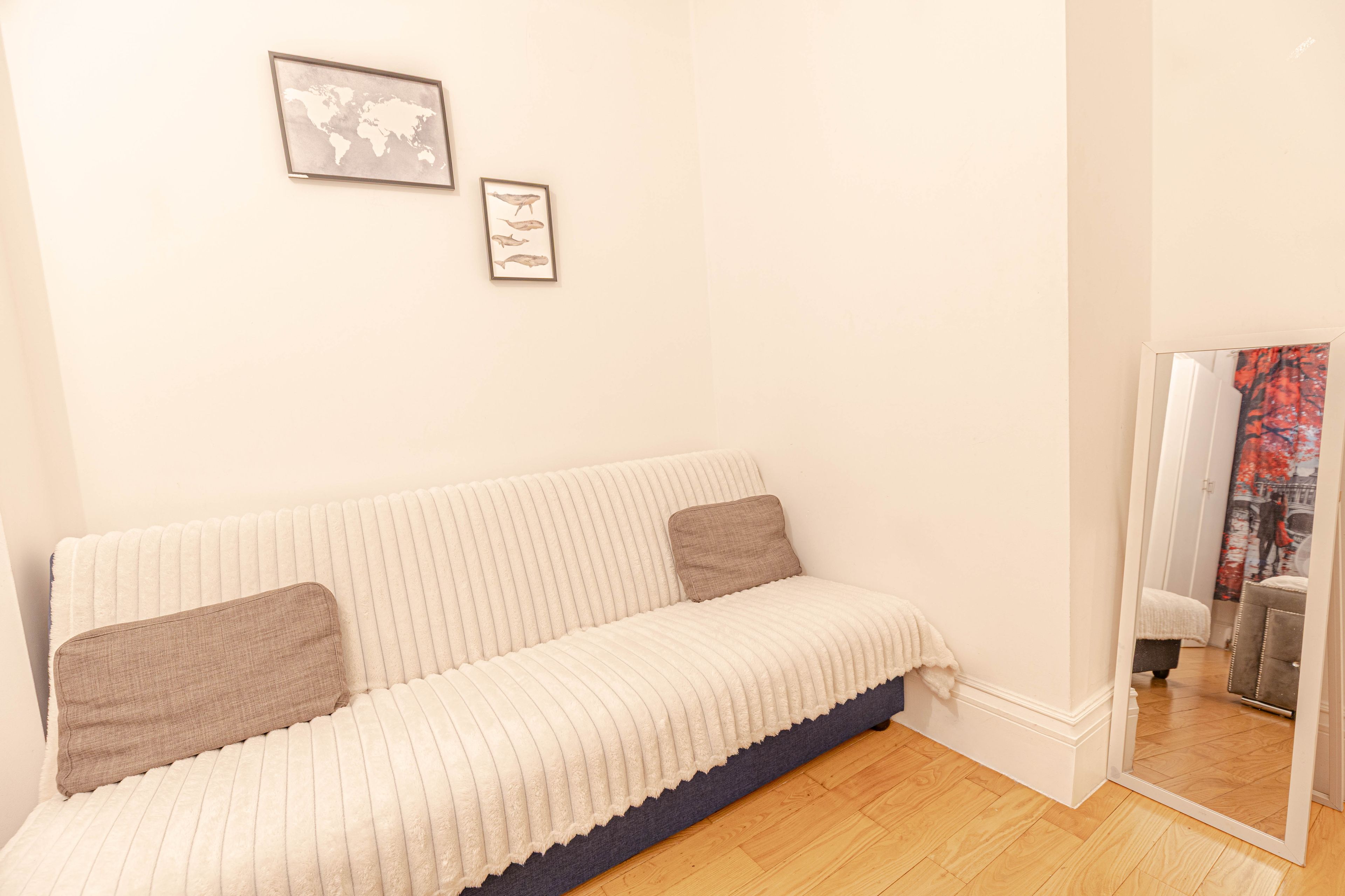 Een kamer met een witte bank, een wereldkaart en een walvisillustratie aan de muur.