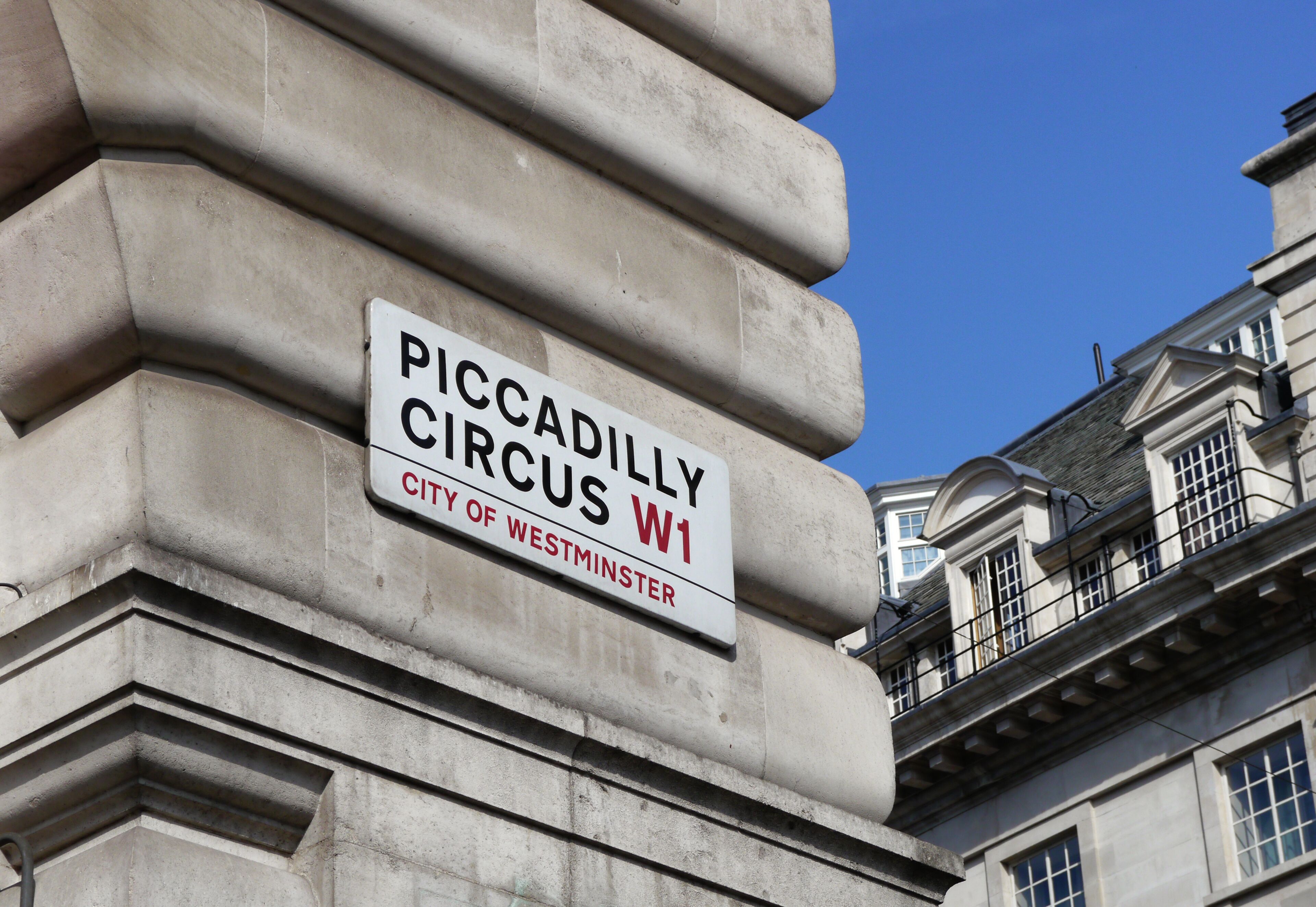 Esquina de un edificio con un cartel que dice 'Piccadilly Circus W1, City of Westminster'.