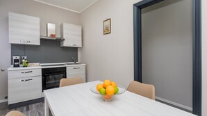 Een moderne keuken met witte kasten, een ingebouwde oven en een eettafel met een fruitschaal.