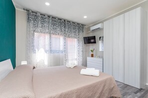 A bedroom with a bed, a TV, a wardrobe, and a window with curtains.