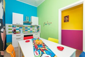 A brightly colored kitchen with a white table, a fruit bowl, and a red bowl.