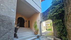 A stone staircase leading to a doorway, a potted plant, and a view of a garden through an archway. - The TABIAT Apartment - Grandpa AngeloIl's HOUSE (Capo di Ponte)