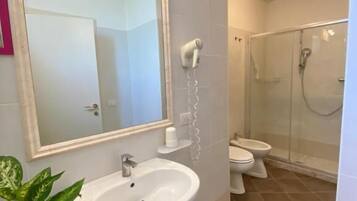 Un baño con lavabo, espejo, ducha e inodoro.