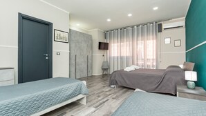 Een slaapkamer met twee bedden, een televisie en een grijze stoel.