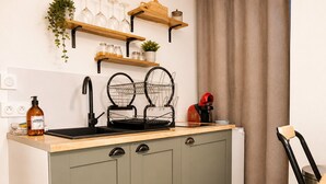 A kitchen with a wooden countertop, a sink, a coffee machine, and a plant on a shelf. - Cosy apartment in the historic district of La Doutre - 2 guests (Angers)