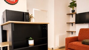 A modern living room with a black entertainment unit, a red sofa, and a potted plant. - Cosy apartment in the historic district of La Doutre - 2 guests (Angers)