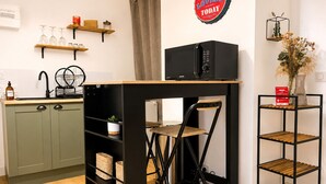 A compact kitchen with a foldable table, a microwave, and a small shelf with a plant. - Cosy apartment in the historic district of La Doutre - 2 guests (Angers)