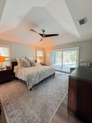 A bedroom with a bed, a ceiling fan, a large window, and a view of a pool. - Luxury 4 Bedroom Family Pool Home (Stuart)