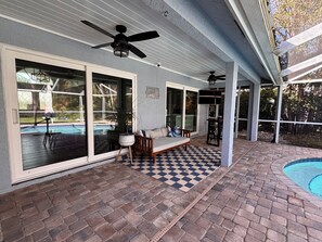 A covered patio with a pool, a bench, and a ceiling fan. - Luxury 4 Bedroom Family Pool Home (Stuart)