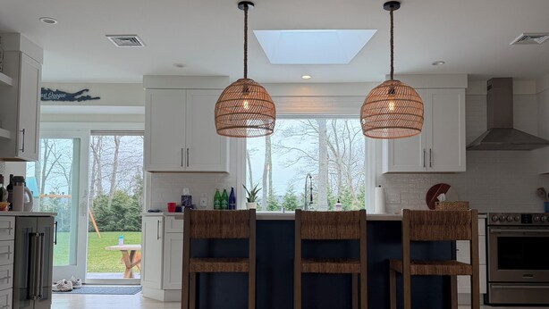 A modern kitchen with a central island, pendant lighting, and a view to the outdoors. - Peaceful and updated 4-bedroom house in East Quogue (East Quogue)