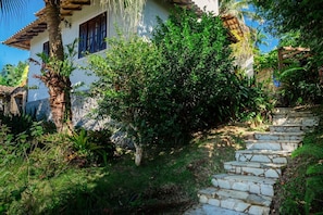 A stone staircase leading up to a white building with a tiled roof, surrounded by lush greenery and a palm tree. - Casa com Churrasqueira, Hidro e Vista em Paraty (Paraty)