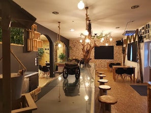 A modern interior with a central tree sculpture, wooden furniture, and a polished floor. - Atlantic Nature Beach House (BARRA DE MIRA)