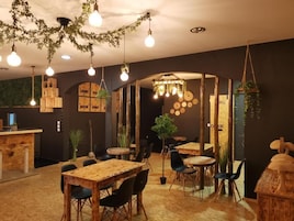 A restaurant interior with wooden tables, hanging light bulbs, and a rustic decor.