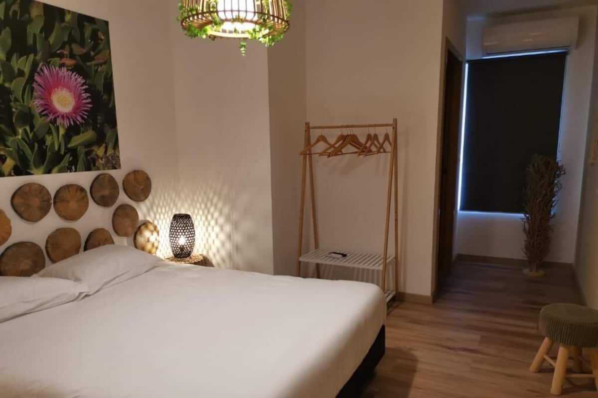Un dormitorio con cama, estante en la pared, perchero y ventana con persianas.