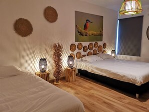 A bedroom with two beds, a wall-mounted artwork of a bird, and a hanging light fixture. - Atlantic Nature Beach House (Mira)