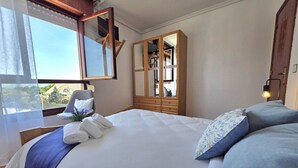 Une chambre d’hôtel avec un grand lit, une armoire, une chaise et une fenêtre avec des rideaux.
