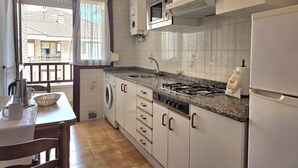 Une cuisine compacte équipée d’un lave-linge, d’un four à micro-ondes, d’une cuisinière à gaz et d’un réfrigérateur.