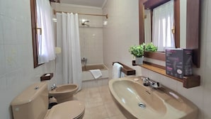 Une salle de bain avec une baignoire, deux lavabos, des toilettes et une douche.