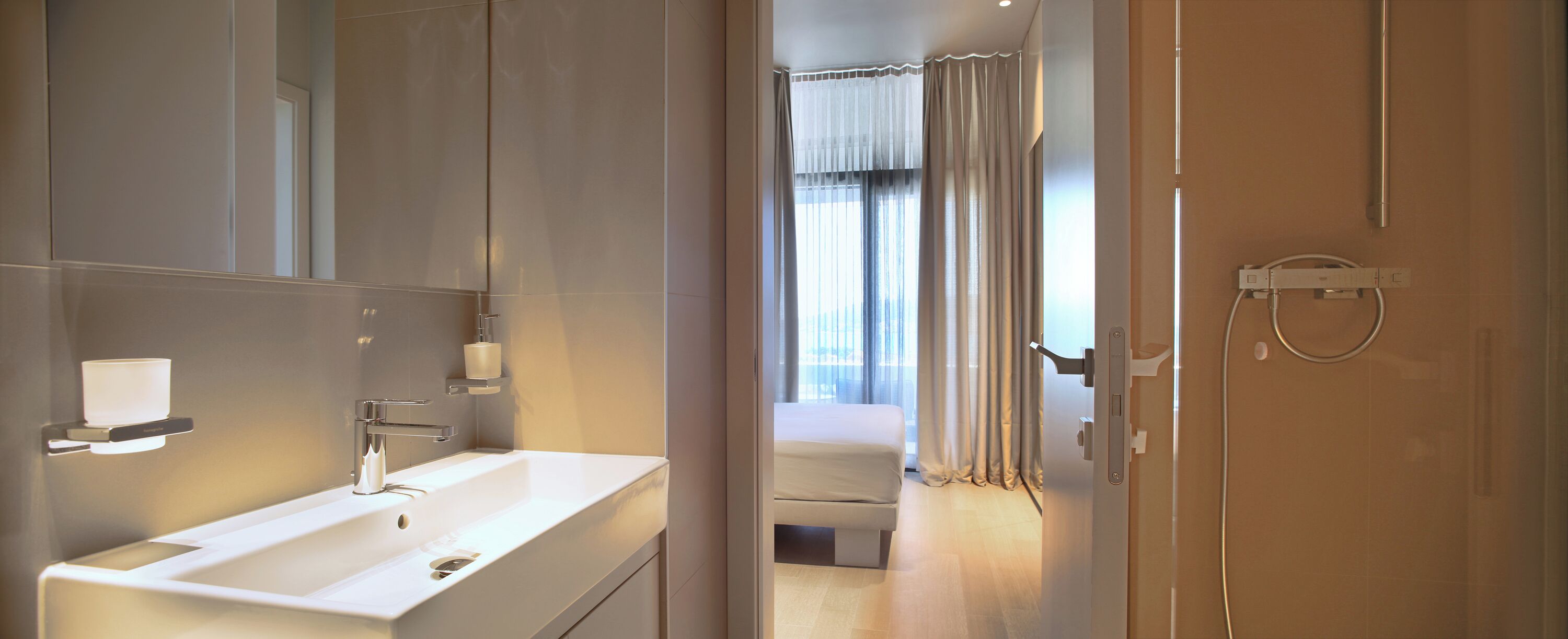 Un baño moderno con un espejo grande, un lavabo blanco y una zona de ducha.