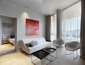 Ein modernes Wohnzimmer mit einer Couch, zwei Sesseln, einem Couchtisch und einem großen abstrakten Gemälde.