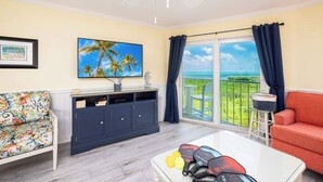 Ein Wohnzimmer mit Balkon, Fernseher, Sofa, Couchtisch und Schrank.