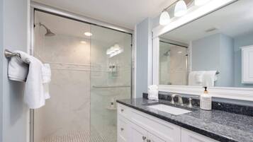 A modern bathroom with a glass shower enclosure, a sink with a vanity, and a large mirror.